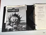 A three-ring binder containing the playtest manuscript for "ManaStorm: The Magic Adventure Game," featuring a black and white cover illustration of a character with a spiked helmet and a weapon. The title "MANASTORM The Magic Adventure Game" is prominently displayed at the top, along with the version number and date on the first page inside the binder. Additional pages include loose character sheets and player handouts, indicating the game's mechanics and spells.