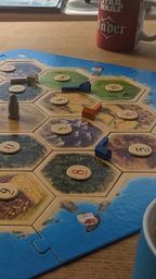 The Catan board laid out as  advised for beginners. On a dining table with tea