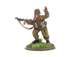 A detailed miniature of a soldier in a military uniform, standing on a circular base adorned with grass and dirt. The figure, representing Augustus Newman VC, is depicted in a dynamic pose, holding a submachine gun in one hand while raising the other in a commanding gesture. He wears a green beret and a khaki uniform, complete with various pouches and gear attached to his chest.