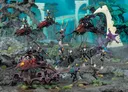 A dynamic scene showcases a group of Harlequin miniatures from Games Workshop, featuring vibrant colors and intricate details. The display includes two Skyweavers and a Starweaver, with Harlequin models in various poses, some wielding weapons and others in dramatic stances. The background features a fantastical landscape with alien flora, enhancing the colorful and theatrical theme of the Harlequins.