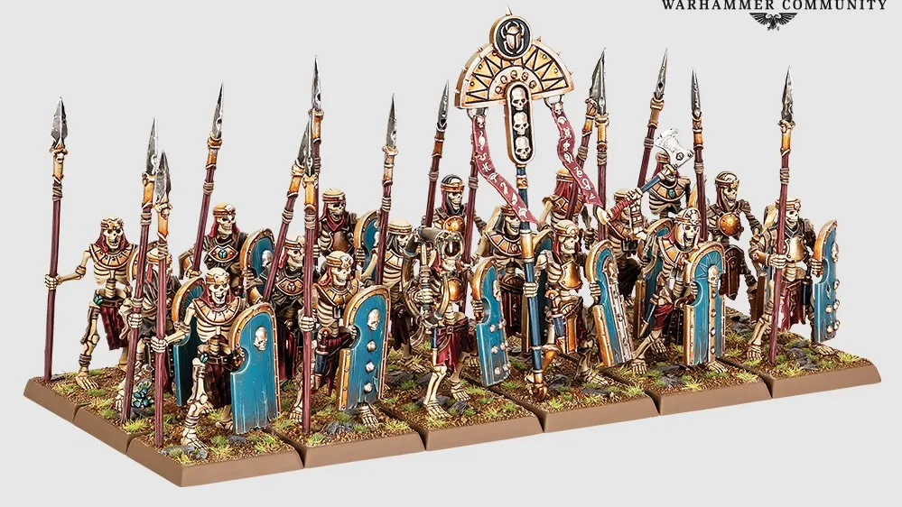 Miniature models of six skeleton chariots with detailed Nehekharan designs, each pulled by two skeletal horses. Chariots carry two skeletal warriors with spears and shields. Background shows skeletal warriors and archers in varied poses, some holding spears, others bows.