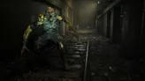 A monstrous, decayed humanoid creature with glowing yellow eyes and exposed, rotting flesh crouches on a set of rusted train tracks in a dimly lit, abandoned station. The creature’s mouth is wide open, revealing sharp teeth, and its arms are outstretched. Debris covers the ground.