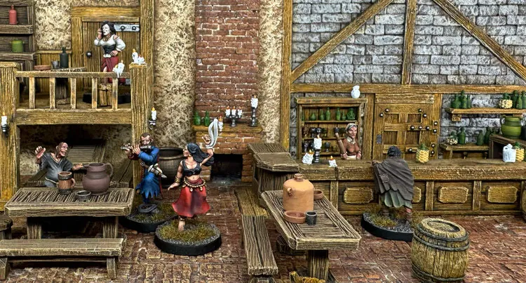 A detailed scene inside a fantasy tavern features several painted miniatures. In the foreground, a woman in a red skirt brandishes a sword, while a man in a blue tunic stands nearby. Behind the bar, a female bartender interacts with a cloaked figure, and various bottles and mugs are visible on the shelves. The tavern's rustic wooden furniture and stone walls create an immersive atmosphere.