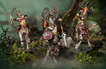 A trio of elven centaur models from the Kurnoth’s Heralds warband stands prominently in a lush, forested setting. Each figure is intricately detailed, featuring ornate armor and antlered helmets, with vibrant colors highlighting their unique designs. The central figure wields a spear and shield, while the others are posed with weapons, showcasing their readiness for battle amidst a backdrop of moss and twisted branches.