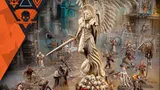 The image features a striking centerpiece statue of a winged figure, wielding a sword and adorned in ornate armor, surrounded by various miniatures representing the new Kill Team expansion. In the foreground, a group of ecclesiarchal militiamen, known as Sanctifiers, can be seen, including a Confessor and a small cherub, while in the background, the ferocious Goremongers, led by a Blood Herald, are positioned menacingly. The setting is richly detailed, with a backdrop of industrial ruins, enhancing the dramatic atmosphere of the scene.