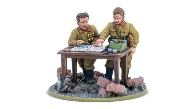 A detailed miniature scene features two Soviet officers, one with a map and the other pointing at it, engaged in strategic planning. They are dressed in military uniforms with insignia, standing beside a table cluttered with a map, a green box, and other items. The base is set on a rubble-strewn ground, with a small animal visible in the foreground, enhancing the war-torn atmosphere.