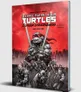 Cover of Teenage Mutant Ninja Turtles & Other Strangeness RPG book. Red gradient background with city skyline. Central figure: large, muscular turtle in red mask and bandana holding two swords. Four smaller turtles in similar poses behind.