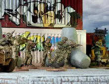 Five toy soldiers in camouflage aim rifles behind a graffiti wall.