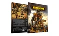 A hardcover rulebook for Warmachine is prominently displayed, featuring a striking cover with a large, armored warjack on the front. The back cover showcases a group of detailed miniatures in a rocky terrain, depicting various warcasters and constructs engaged in battle. Text highlights the core themes of the game, including its rich lore and the ongoing conflict in the Iron Kingdoms, while the spine of the book is labeled "CORE BOOK."