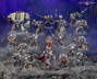 A detailed display of Black Templar miniatures showcases a variety of armored figures in silver and black, set against a dark, rocky backdrop. Prominent in the scene is a Venerable Dreadnought on the left, flanked by a mix of characters including the Emperor’s Champion, Bladeguard Veterans, and Sword Brethren, all wielding swords and other weapons. The figures are intricately painted, with some holding banners and others poised for battle, creating a dynamic and imposing presence.