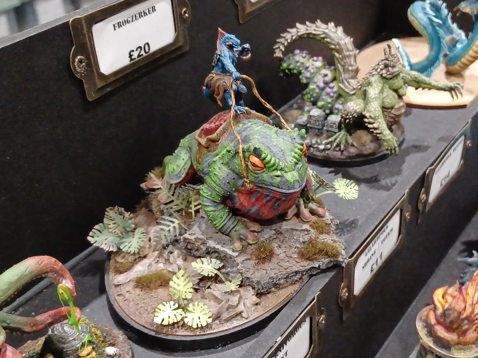 A vibrant miniature display features a large, colorful frog-like creature, known as