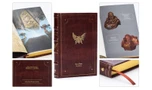 A special edition hardcover book titled "Era of Ruin: The Anthology" features a rich red faux-leather cover adorned with a prominent gold emblem of an eagle. The book showcases intricate debossed details and gold gilt page edges, along with a ribbon bookmark. Surrounding the book are images of its interior, displaying full-color artwork and a quote that reads, "All we have left now are stories."