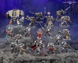 A detailed display of Black Templar miniatures showcases a variety of armored figures in silver and black, set against a dark, rocky backdrop. Prominent in the scene is a Venerable Dreadnought on the left, flanked by a mix of characters including the Emperor’s Champion, Bladeguard Veterans, and Sword Brethren, all wielding swords and other weapons. The figures are intricately painted, with some holding banners and others poised for battle, creating a dynamic and imposing presence.
