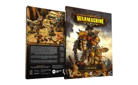A hardcover rulebook for Warmachine is prominently displayed, featuring a striking cover with a large, armored warjack on the front. The back cover showcases a group of detailed miniatures in a rocky terrain, depicting various warcasters and constructs engaged in battle. Text highlights the core themes of the game, including its rich lore and the ongoing conflict in the Iron Kingdoms, while the spine of the book is labeled "CORE BOOK."