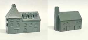 A detailed model of a building designed for 6mm scale wargames, featuring a sloped roof with three dormer windows and a textured surface that resembles slate. The facade includes several arched and rectangular windows, along with a large door at the base, all rendered in a light gray resin. The overall design suggests an industrial style, suitable for various historical or modern warfare settings.