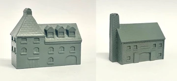 A detailed model of a building designed for 6mm scale wargames, featuring a sloped roof with three dormer windows and a textured surface that resembles slate. The facade includes several arched and rectangular windows, along with a large door at the base, all rendered in a light gray resin. The overall design suggests an industrial style, suitable for various historical or modern warfare settings.