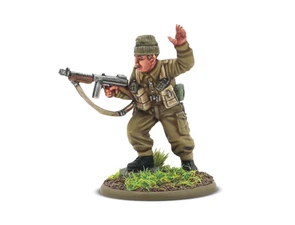 A detailed miniature of a soldier in a military uniform, standing on a circular base adorned with grass and dirt. The figure, representing Augustus Newman VC, is depicted in a dynamic pose, holding a submachine gun in one hand while raising the other in a commanding gesture. He wears a green beret and a khaki uniform, complete with various pouches and gear attached to his chest.