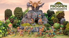 A vibrant scene showcases a variety of colorful Space Frogmen miniatures, including a frogman chieftain and cavalry, positioned around a rocky outcrop adorned with ancient symbols and a large decorative skull. Lush greenery and spiky plants surround the figures, enhancing the fantastical atmosphere. The text "FROGMEN REINFORCEMENTS" is prominently displayed in the corner, indicating the theme of the Kickstarter campaign.