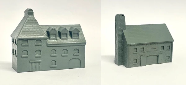 A detailed model of a building designed for 6mm scale wargames, featuring a sloped roof with three dormer windows and a textured surface that resembles slate. The facade includes several arched and rectangular windows, along with a large door at the base, all rendered in a light gray resin. The overall design suggests an industrial style, suitable for various historical or modern warfare settings.