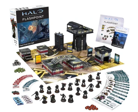 A boxed set for Halo: Flashpoint titled "Feet First into Hell" is prominently displayed, featuring artwork of soldiers in combat. Surrounding the box are 18 detailed miniatures of Orbital Drop Shock Troopers, along with a play mat depicting an urban warzone, several buildings, and various game components including dice, tokens, and cards. The scene is organized, showcasing the miniatures in a dynamic layout, emphasizing the tactical elements of the game.