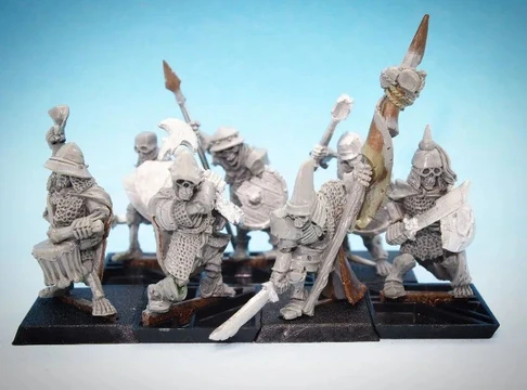 A collection of 28mm scale skeleton warriors from Diehard Miniatures, featuring several figures in various poses. The miniatures are equipped with weapons such as spears and swords, and are adorned with armor and helmets reminiscent of classic Oldhammer designs. The background is a soft blue gradient, highlighting the details of the skeletal figures, which are mounted on black bases.