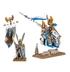 A detailed display of two high-elf miniatures from the Age of Sigmar universe. On the left, a standard bearer holds a banner adorned with a blue and gold design, featuring a lion motif. On the right, a mounted high-elf lord, clad in ornate armor with blue and gold accents, raises a spear, showcasing intricate details and a flowing cape, while standing on a scenic base with rocky terrain.