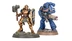 A detailed miniature of a Stormcast Eternal stands on the left, wearing ornate armor with a golden finish, holding a large hammer in one hand and a shield emblazoned with a lightning symbol in the other. To the right, a blue-armored Infernus Space Marine is depicted, equipped with a bolter and showcasing intricate details on its armor. Both miniatures are positioned on textured bases with patches of grass, emphasizing their dynamic poses.