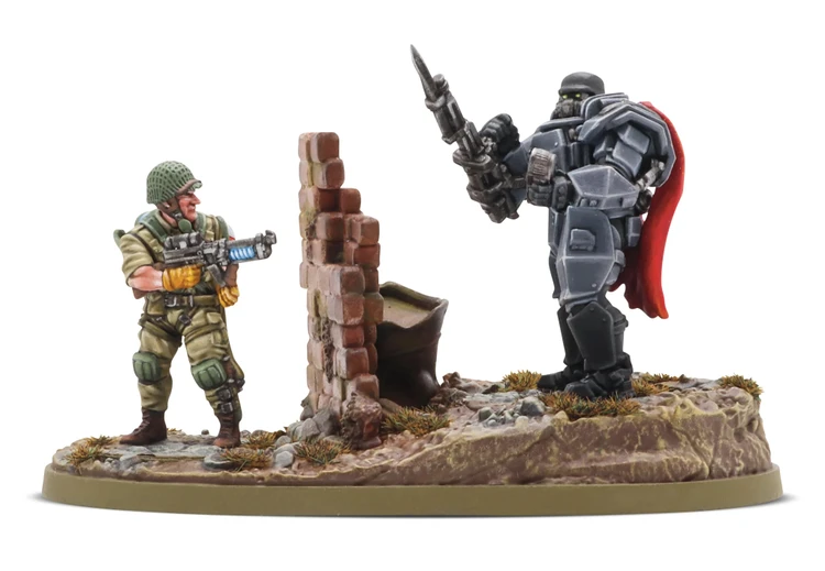 A detailed miniature scene features a soldier in military attire, holding a futuristic weapon, standing beside a crumbling brick wall. Opposite him, a heavily armored mech with a prominent red cape stands confidently, brandishing a spear-like weapon. The base is textured with grass and rocks, enhancing the dynamic and gritty atmosphere of the setting.