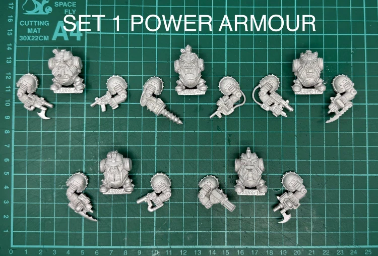 A collection of multipart, white metal miniatures featuring armoured dwarves, arranged on a green cutting mat with a grid pattern. The top row displays various dwarf figures in sci-fi power armour, each equipped with different weapons, including a drill and firearms. The text