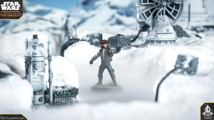 A Rebel Officer stands prominently in a snowy landscape, wearing a brown jacket and a red cap, with one hand raised as if giving orders. In the background, a detailed speeder truck and various mechanical structures are partially obscured by snow, creating a wintry atmosphere. The scene is set against a backdrop of distant mountains under a clear blue sky.