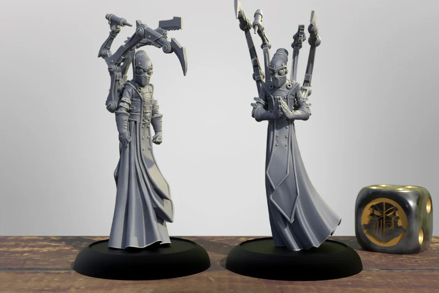 Two detailed 3D printed miniatures stand on black bases, showcasing the Cephalyx Mind Slayers from the Warmachine universe. Each figure is dressed in long, flowing robes and features a distinctive mask, with one holding a pair of mechanical arms equipped with weapons, while the other has its hands clasped in a gesture of focus. The background is a simple gradient, emphasizing the intricate designs of the miniatures, with a decorative die featuring a symbol from the game placed nearby.
