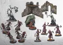 Miniature figures, stone ruins, and a green dumpster on a gray tiled floor.