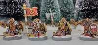 Three painted miniature figures of fantasy dwarves stand on round bases in a snowy outdoor setting with blurred evergreen trees in the background.

The left figure wears a horned helmet, patterned tunic, and fur cloak, holding a pole-mounted red banner with a gold emblem of a snarling face. The figure also carries a round shield on their back.

The center figure, slightly behind the others, wears a helmet with a nose guard, a fur-lined cloak, and carries a pole weapon with a curved blade.

The right figure, holding a large double-bladed axe over one shoulder, wears a horned helmet, fur cloak, and patterned tunic. Their beard is braided and wrapped around their waist.