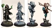 Two intricately designed female miniatures are displayed on circular bases. On the left, a dark-haired sorceress holds a staff topped with a skull and emits a green magical aura from her other hand, dressed in a revealing outfit with flowing garments. The right miniature features a blonde spellcaster with arms raised, adorned in a similarly revealing outfit, showcasing detailed sculpting and characterful poses. Both miniatures are presented in a mix of painted and unpainted finishes, highlighting their intricate details.