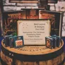 Award plaque on barrel with Warhammer books, dice, and boxes.