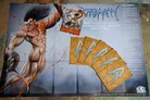 The image features a game board for the card game "Barbarity," prominently displaying a muscular barbarian character with long, wild hair and a fierce expression, depicted in a dynamic pose. The background is splattered with red, suggesting a violent theme. To the right, there are several game cards, including one labeled "Warpo Mac Spasm," alongside a set of prize cards that have a textured, brown appearance with stylized blue markings. The board has designated areas for adventure cards, emphasizing the game's focus on combat and resource management.