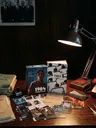 Cluttered desk with "1984 Unperson" game, lamp, phone, papers, and ashtray.