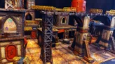 A detailed tabletop scene showcases a grimdark, sci-fi urban environment with various structures made from textured materials, featuring rusted metal and weathered surfaces. Prominent elements include tall support beams, stacked containers, and buildings adorned with graffiti and signage, all set on a gritty, tiled ground. Elevated walkways connect the structures, enhancing the industrial feel of the UnderNidus District.
