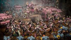 The image features a dynamic scene filled with a multitude of Emperor’s Children miniatures from the Warhammer 40,000 universe, showcasing their vibrant pink and purple color scheme. In the foreground, a diverse array of Chaos Space Marines, adorned with ornate armor and chaotic symbols, engage in battle, while a towering, menacing figure looms behind them, possibly a Daemon Engine or a warlord. Several vehicles, including armored transports, are also present, adding to the chaotic atmosphere of the battlefield, which is set against a dark, atmospheric backdrop. The overall composition emphasizes the flamboyant and hedonistic nature of the Emperor’s Children, reflecting their devotion to Slaanesh.