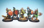 A group of five intricately painted orc miniatures stands on a textured black base, showcasing a variety of weapons and armor. Each orc features distinct details, such as shields with unique designs, including a fierce red face, and various outfits that highlight their individual characteristics. The background is a soft gradient of blue, enhancing the vibrant colors of the miniatures.