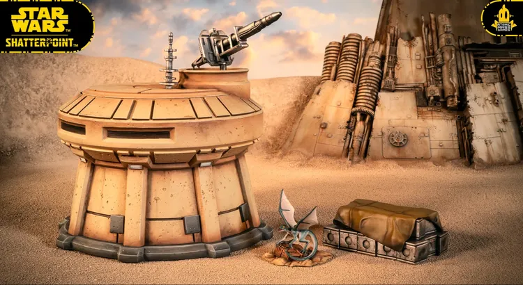 A detailed terrain setup features a sandy landscape with a large, weathered structure in the background, showcasing various mechanical elements and textures. In the foreground, a small, futuristic outpost with a rounded top is positioned next to a covered crate, while a small creature with blue wings and a scaly body rests nearby. The overall scene evokes a desolate yet intriguing atmosphere, suitable for tabletop gaming.