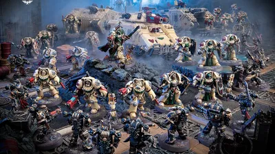 Miniature Space Marines in armor, some holding weapons, with tanks and ruins in the background.