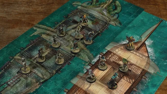 A tabletop gaming map with a nautical theme, featuring two wooden ship decks connected by a plank. Miniature figures are positioned on the decks and plank, depicting various characters in dynamic poses. The background includes a greenish-blue ocean with stylized waves and a large tentacle-like structure emerging from the water. The map has a textured, illustrated appearance.
