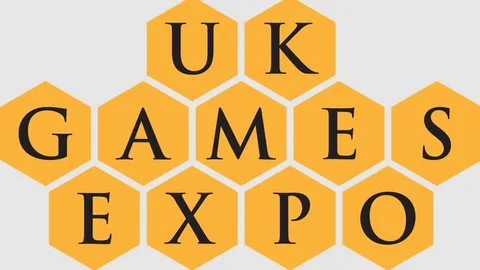 The design features the text "UK GAMES EXPO" arranged in a honeycomb pattern, with each letter placed inside a yellow hexagon. The font is bold and black, creating a strong contrast against the yellow background. The overall layout emphasizes the event's branding in a visually engaging manner.