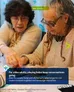 Two older adults sitting at a table, closely examining a board game with small components. One wears glasses and a patterned jacket, the other wears glasses, a beige top, and a necklace. Green label in top-right corner reads "Older adults."