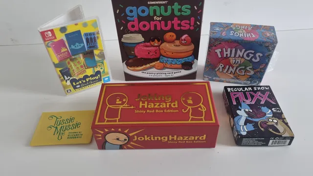 "gonuts for donuts!", "THINGS in RINGS", "Joking Hazard", "Regular Show FLUXX" board game boxes on a white surface.