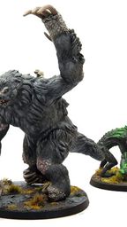The image features three miniatures from Modiphius’ Fallout: Wasteland Warfare line. On the left is a snallygaster, a hexapod creature with a reddish-brown body, multiple eyes on its back, and a long, protruding tongue. In the center stands a large, muscular megasloth, covered in gray fur, with a menacing pose and a raised arm. To the right is another creature, possibly a variant of the snallygaster, in green, with a textured body and large eyes, all set on circular bases adorned with tufts of grass.