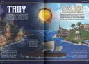 Large, stylized gold letters spelling "TROY" on the left and "TELD" on the right, with the "Y" in "TROY" and the "E" in "TELD" sharing a circular design. The circle features a glowing sun partially obscured by a stylized Trojan Horse head in silhouette. Below the text, a split-scene illustration shows two contrasting landscapes.

On the left, a fortified city with high walls and towers burns under a dark, cloudy sky. Flames rise from buildings near the water. A wooden horse stands on the shore, and a ship with furled sails is visible in the distance.

On the right, a peaceful coastal scene under a bright blue sky with scattered clouds. Rolling green hills with purple flowers lead down to a calm sea. A small temple or shrine sits on a cliff overlooking the water, and three ships with white sails approach the shore.