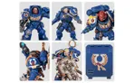 A collection of Ultramarine miniatures showcases various Space Marine figures in blue armor, each featuring distinct details and accessories. The top row includes a character with a prominent helmet and ornate chest emblem, alongside two other figures with different poses and weaponry. The bottom row features a close-up of a figure holding a weapon, another with a skull motif on the armor, and a character wielding a large, intricately designed shield. Additionally, a transfer sheet with various decals is visible, featuring Ultramarine symbols and decorative borders.