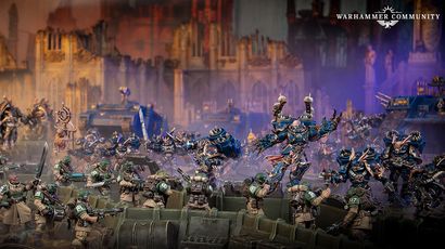 A dynamic scene features a group of intricately detailed Warhammer 40,000 miniatures engaged in battle. In the foreground, several armored soldiers in green uniforms are positioned behind a barricade, aiming their weapons. In the background, imposing figures in dark blue armor, adorned with spikes and intricate designs, advance menacingly, showcasing a mix of futuristic and gothic architecture in the blurred backdrop.